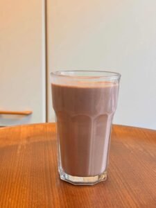 Ein Glas Schokoladen-Smoothie steht auf einem hölzernen Tisch.