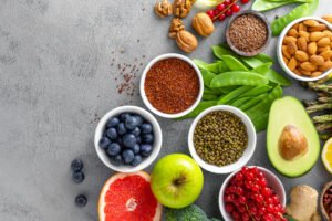 Healthy food background, spinach, quinoa, apple, blueberry, asparagus, turmeric, red currant, broccoli, mung bean, walnuts, grapefruit, ginger, avocado, almond, green peas and goji, top view